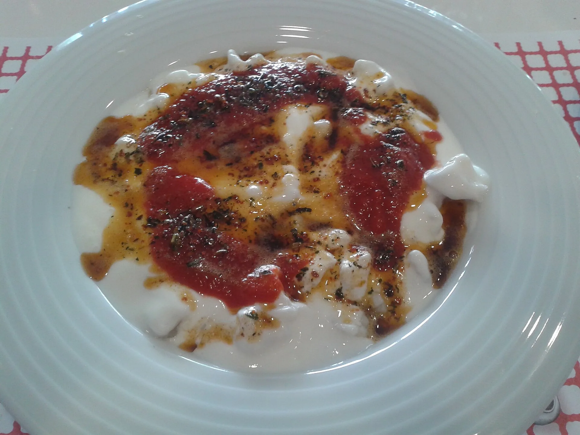 Taça de mantı turco com iogurte, tomate e especiarias