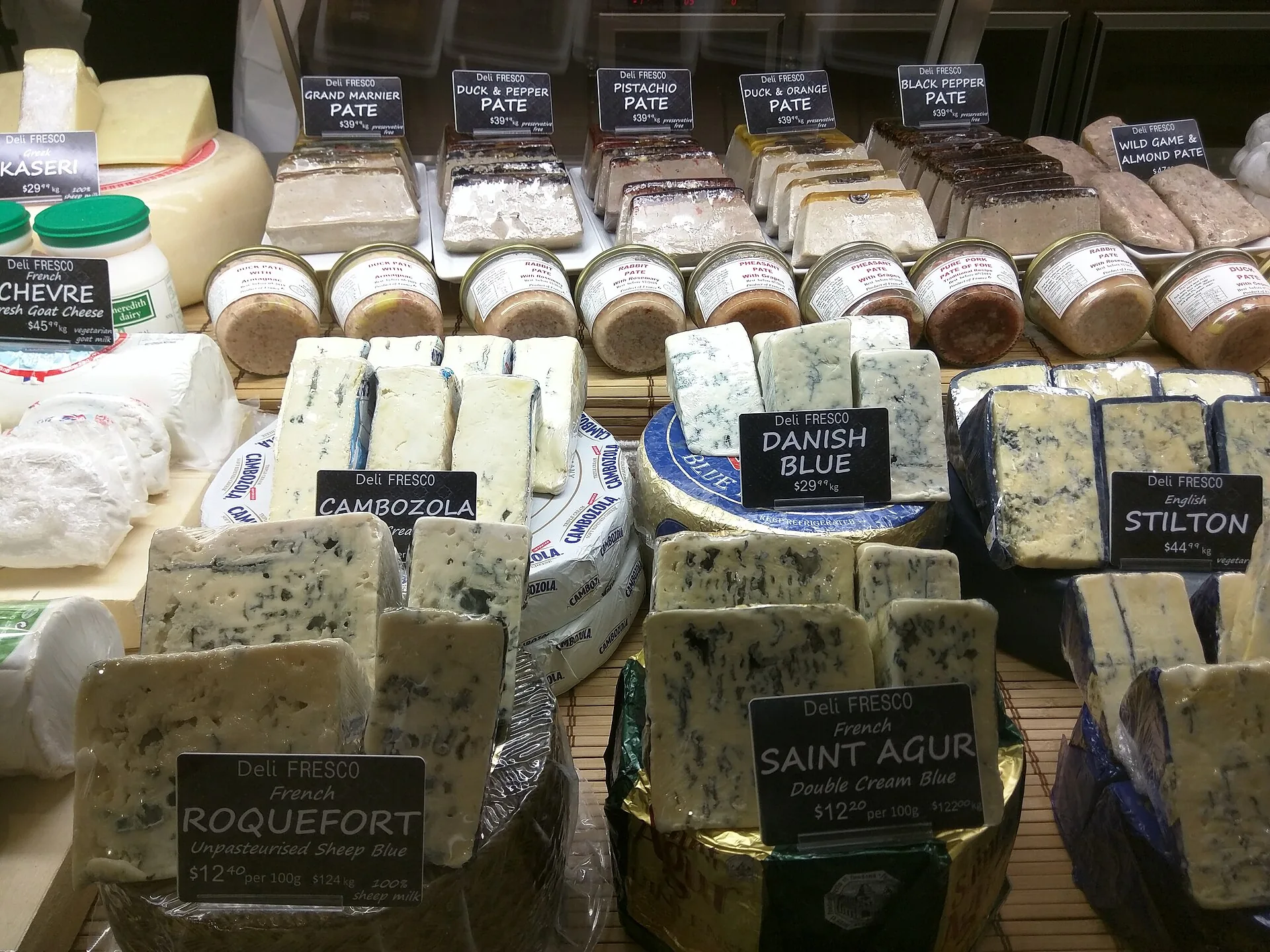 Queijos azuis variados, incluindo Roquefort, numa vitrina de charcutaria